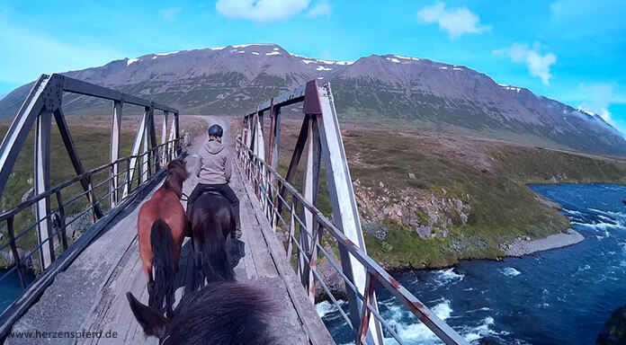 Reiterin mit Handpferd überquert einen Gletscherfluss im Skagajord, Island