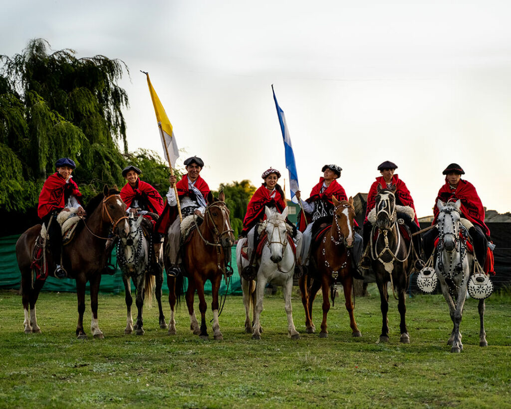 Eine Grupper junger Gauchos in traditioneller Kleidung auf ihren Pferden.